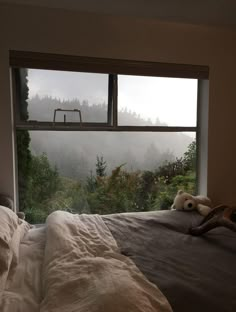 a dog laying on top of a bed in front of a window with a view