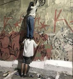 two men are painting graffiti on a wall