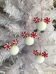 three ornaments hanging from a white christmas tree with candy canes on it's balls