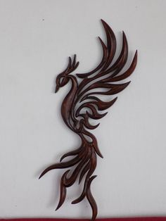 a decorative wooden wall hanging with a bird design on it's face and tail