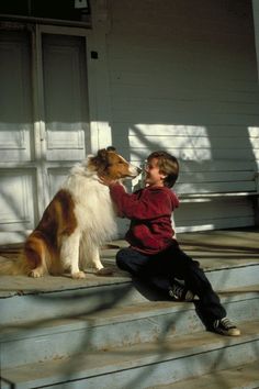 a young boy sitting on the steps with his dog