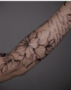 a woman's arm with flowers on it and writing on the side of her arm