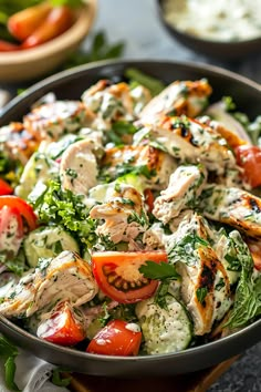 a salad with chicken and tomatoes in a bowl on a table next to other dishes