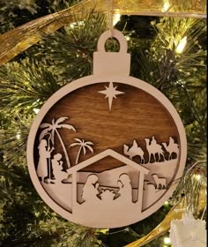 a christmas ornament hanging from a tree with nativity scene in the center