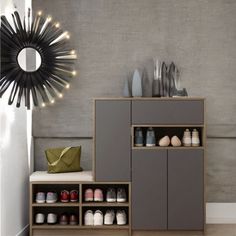 a cabinet with shoes on it in front of a mirror and wall mounted light fixture