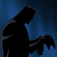 the silhouette of batman holding an object in his hand