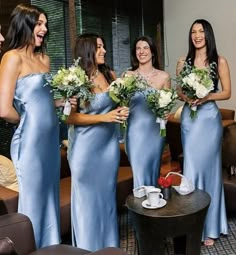 the bridesmaids are laughing together in their blue gowns and holding bouquets