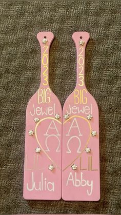 two pink paddles with gold lettering on them