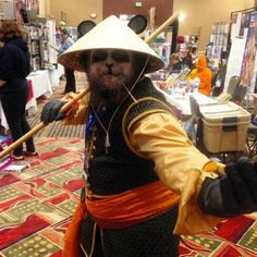 a man dressed up as a pirate holding two wooden sticks in one hand and wearing a straw hat on the other