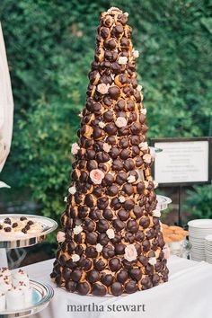 a tall cake with chocolate and flowers on it sitting on a table next to other desserts