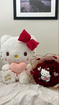 a hello kitty stuffed animal sitting on top of a bed next to a heart shaped pillow