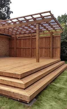 a wooden deck with steps leading up to it and a pergolated area in the background