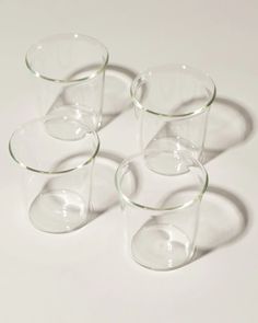 four clear glass cups sitting next to each other