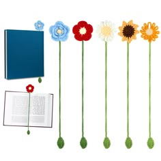 crocheted flowers are arranged next to an open book on a white background,