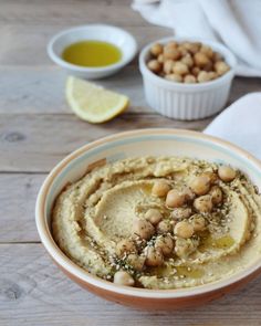 hummus with chickpeas in a bowl next to lemon wedges and pita chips