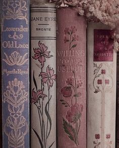 there are many books lined up together on the shelf in front of each other with flowers painted on them