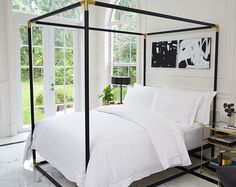 a bed with white sheets and pillows in a room