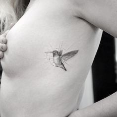 a woman with a small tattoo on her chest holding onto the side of her breast