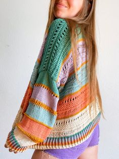 a woman with long hair wearing a multicolored crochet knitted sweater