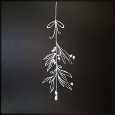 some white flowers are hanging on a black wall and it looks like they have long stems attached to them