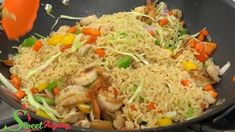 a wok filled with rice and vegetables on top of a stove