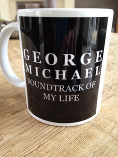 a black and white coffee mug with the words george michael on it sitting on a table