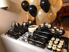 black and white dessert table with balloons, cupcakes, and cake on it