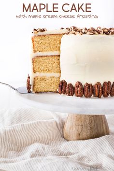 a person is holding a fork near a cake on a white plate with walnuts