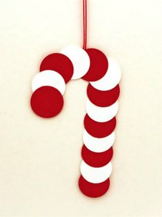 a red and white candy cane ornament hanging from a string on a wall