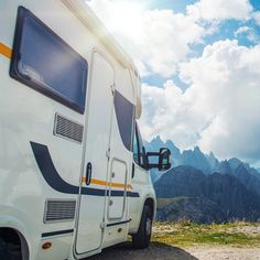 an rv parked on the side of a road with mountains in the background