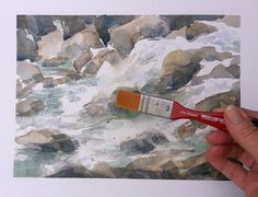 a person holding a paintbrush in their hand and painting rocks on the wall with water