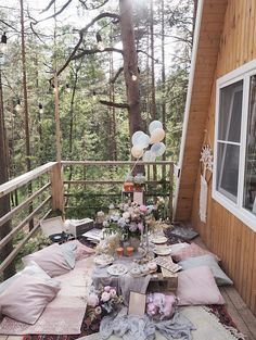 an outdoor table set up on the porch for a picnic party with balloons and confetti