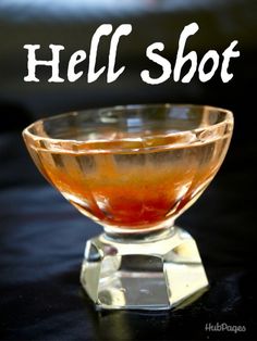 a glass bowl filled with liquid sitting on top of a black table next to the words hell shot