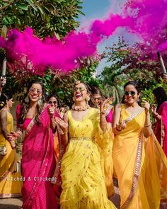 women in yellow and pink saris are throwing colored powder on each other as they walk down the street