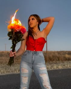 a woman holding a bouquet of flowers on the side of the road in front of her