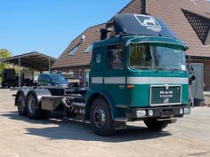 a large green truck parked in front of a building