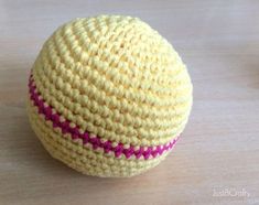 a crocheted yellow and pink ball sitting on top of a wooden table,