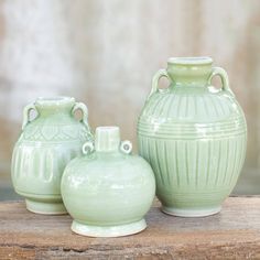 three green vases sitting on top of a wooden table