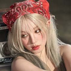 a woman with blonde hair wearing a red bandana and posing in front of an old radio