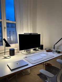 a desk with a monitor, keyboard and mouse on it in front of a window