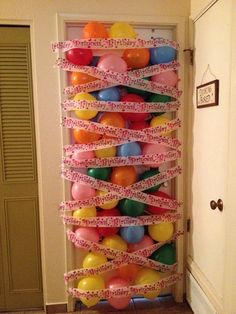 a bunch of balloons that are tied to a wall with some tape on the top