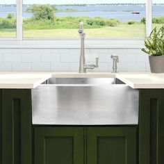 a kitchen sink with green cabinets and a large window in the back drop off wall