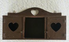 an old wooden wall hanging with two hearts cut out of the front and back of it