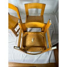 three wooden chairs sitting on top of a white sheet