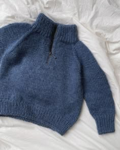 a blue sweater laying on top of a bed