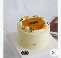 there is a small cake on top of a white box with gold trimmings