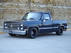 a blue pick up truck parked in front of a stone wall