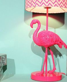 a pink flamingo lamp sitting on top of a table next to a night stand