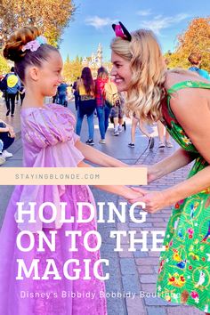 two girls in dresses holding hands with the caption holding on to the magic kingdom