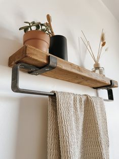 a potted plant is sitting on a shelf above a towel rack that has a metal pipe